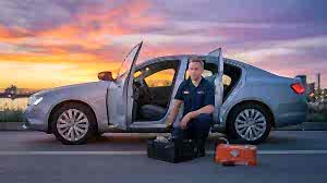 Mobile car locksmith with tool cases beside an unlocked sedan at dusk in Las Vegas