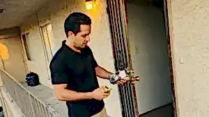 24/7 Locksmith 4U LV technician holding a deadbolt cylinder and a new deadbolt at an apartment door in East Las Vegas